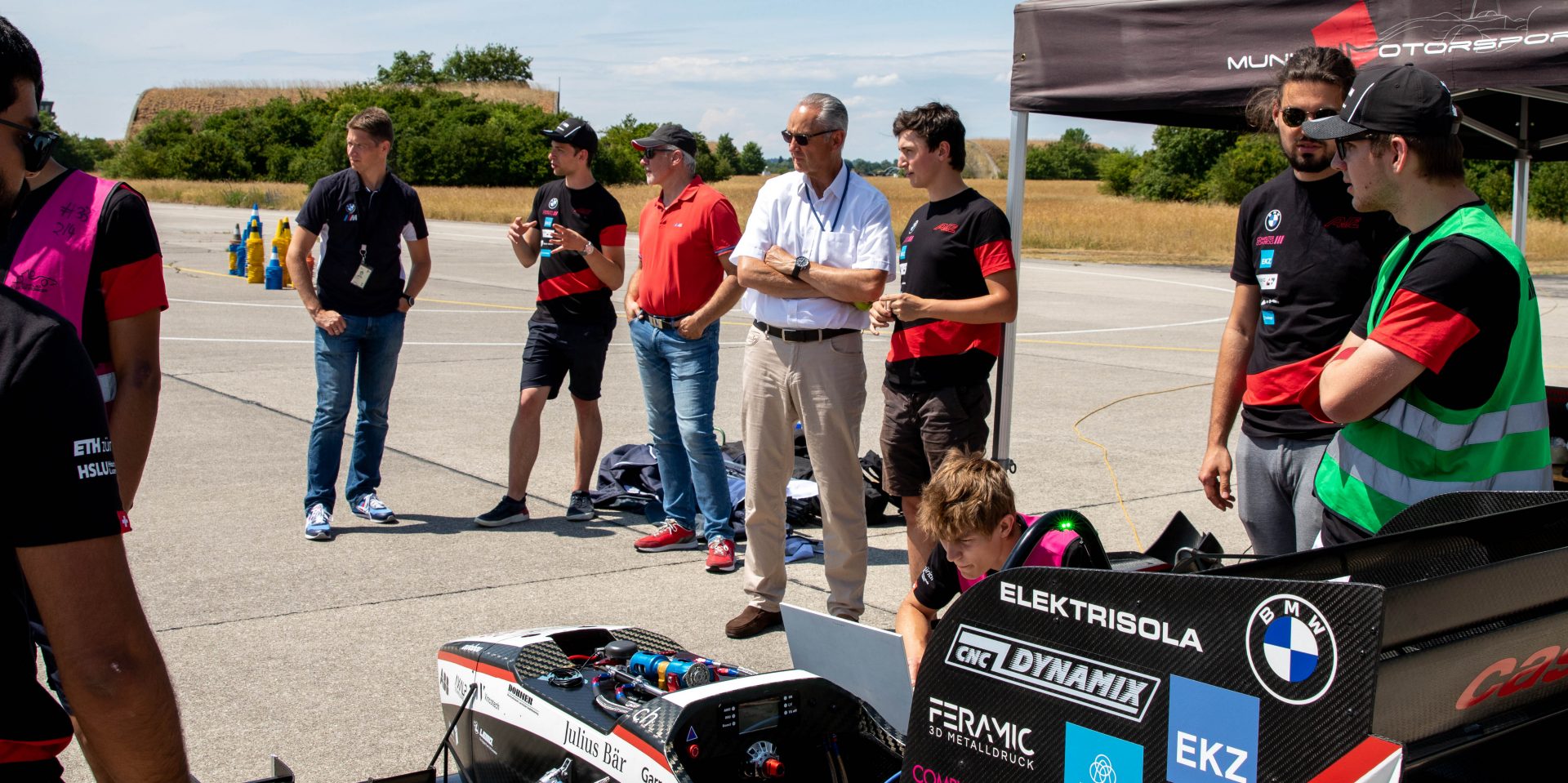 A group of people on the test track having conversations.