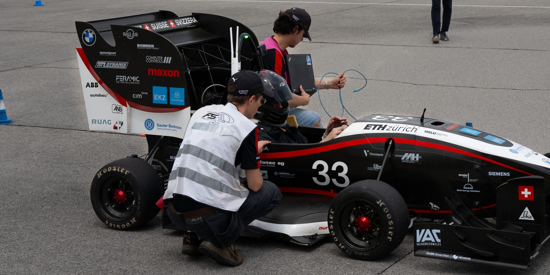 A driver in a race car and a person with a warning vest.