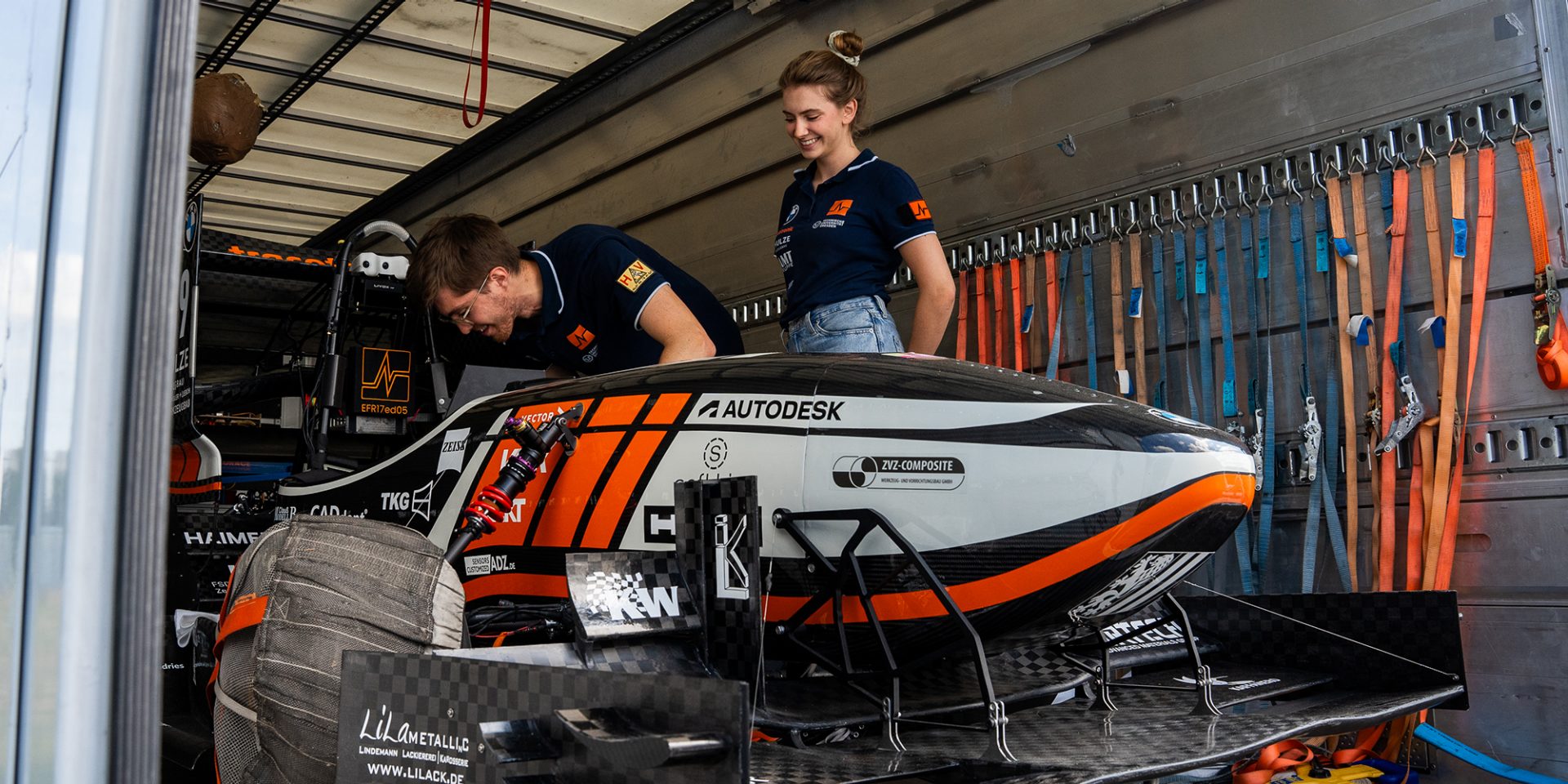 Two young people looking at a race car