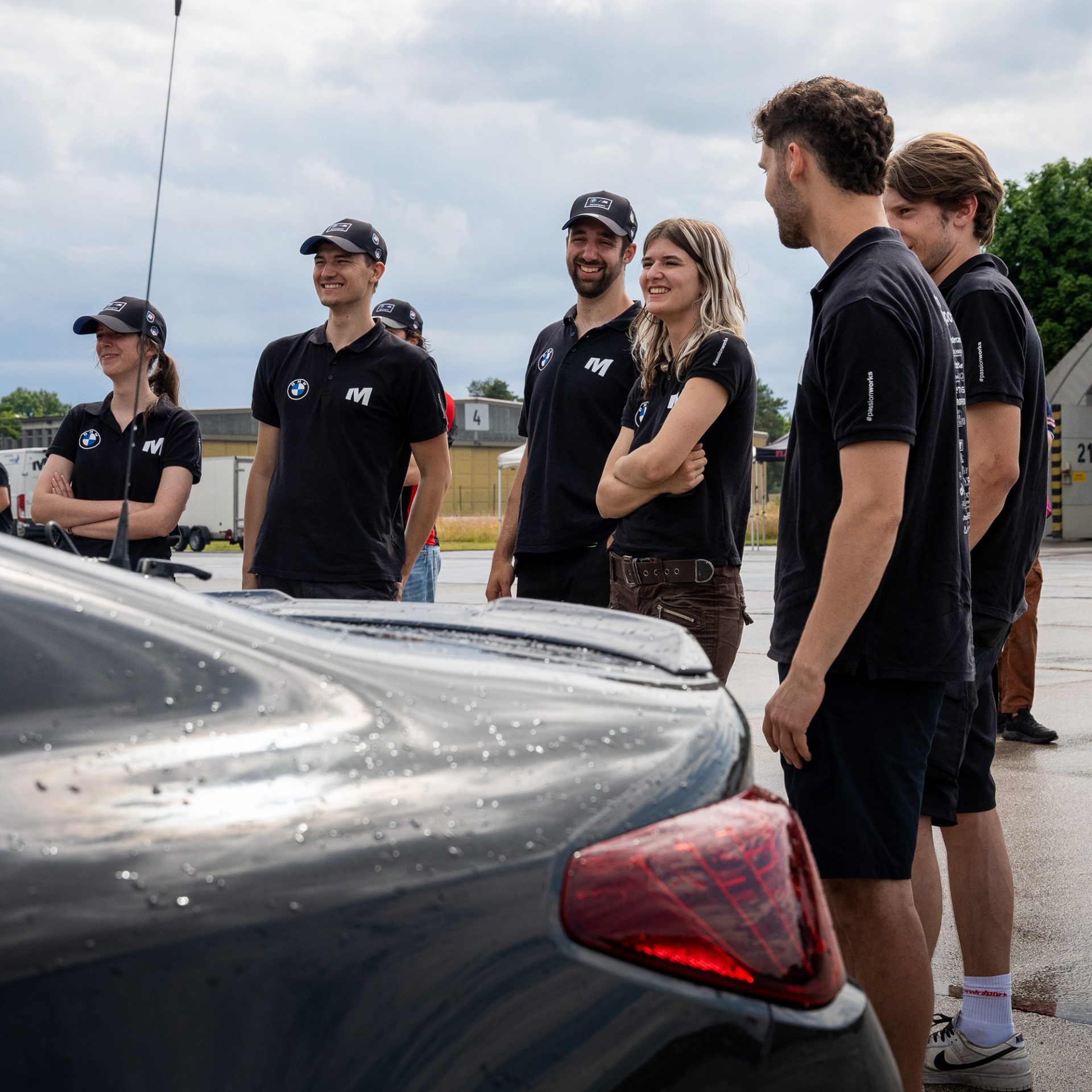 A group of young people standing around a BMW car.