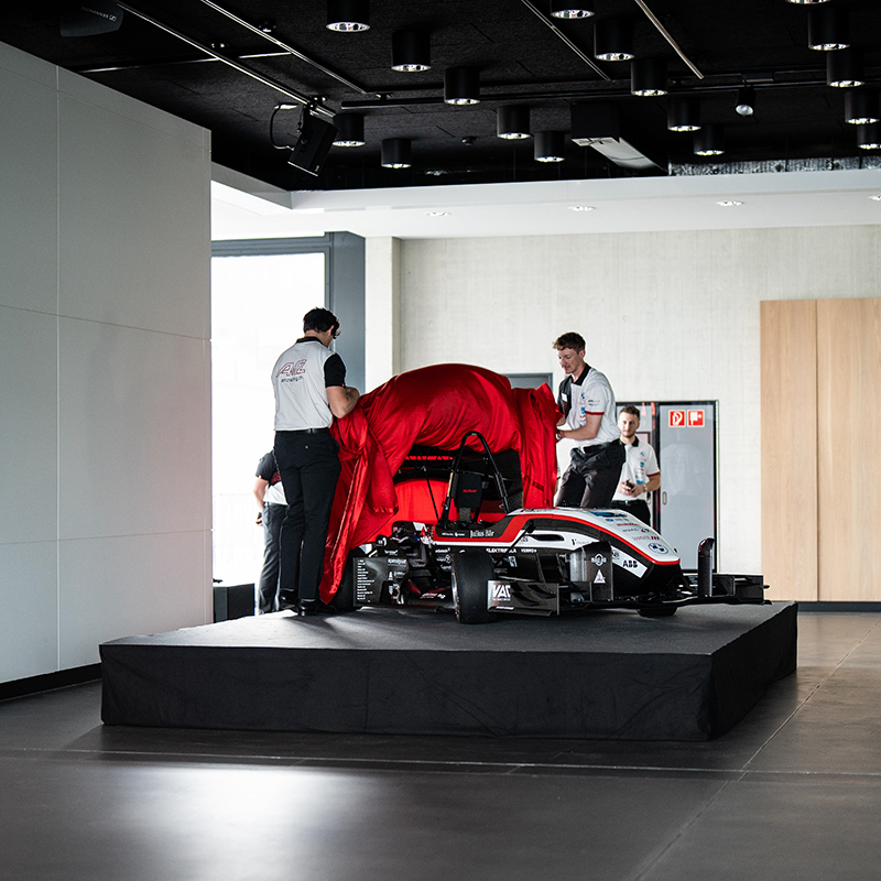 Two students are removing the cover of their race car.