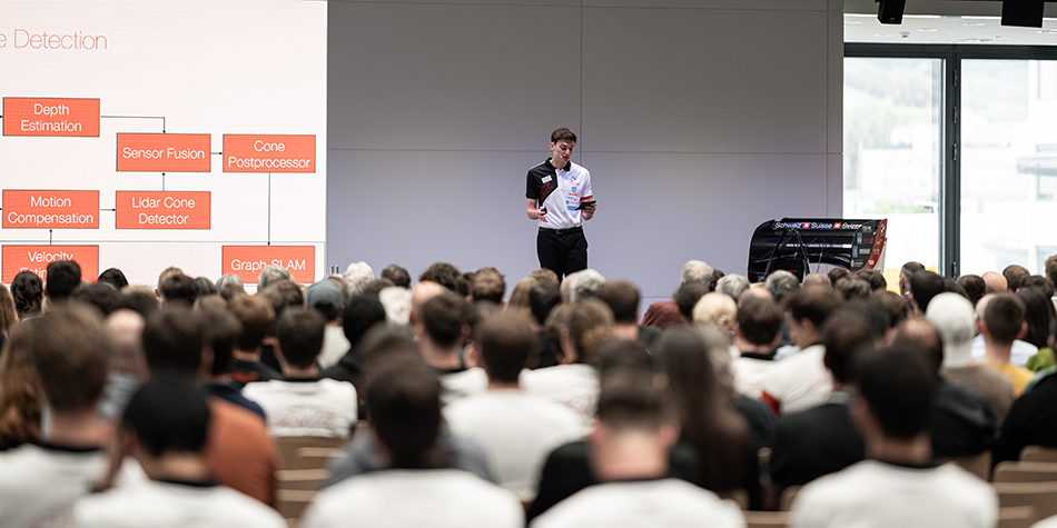 A student is presenting on stage to a group of people.