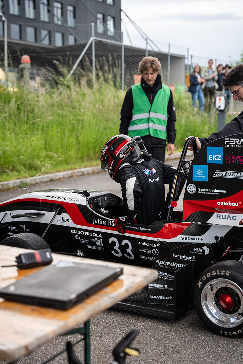A student getting into the race car to start racing.