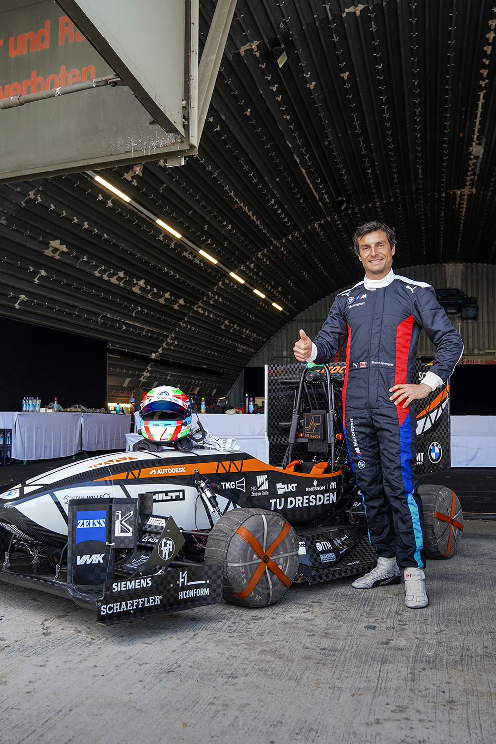 Race driver next to the car giving thumbs-up.