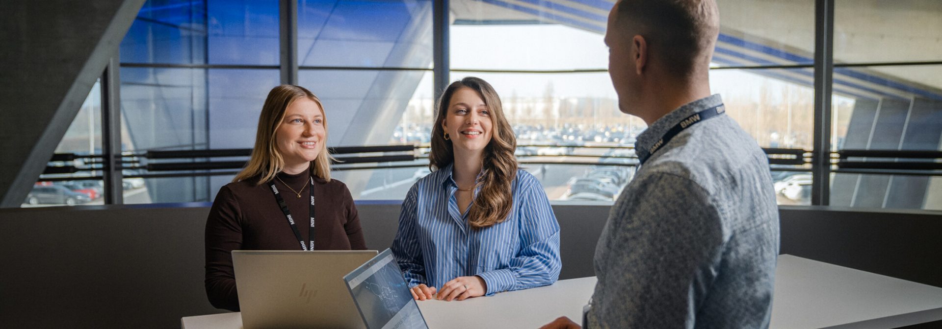 Three BMW Group employees are talking to a Student.