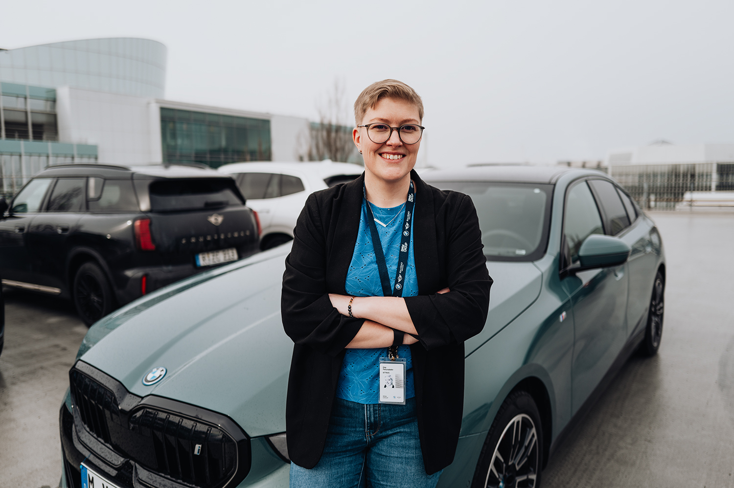 PhD student Erla in a parking lot in front of a BMW i5.