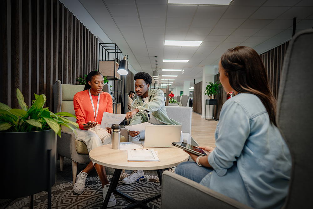 Three students sit at a table and discuss among themselves.