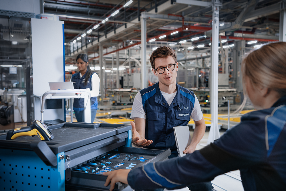 Two colleagues stand next to a toolbox in the factory.