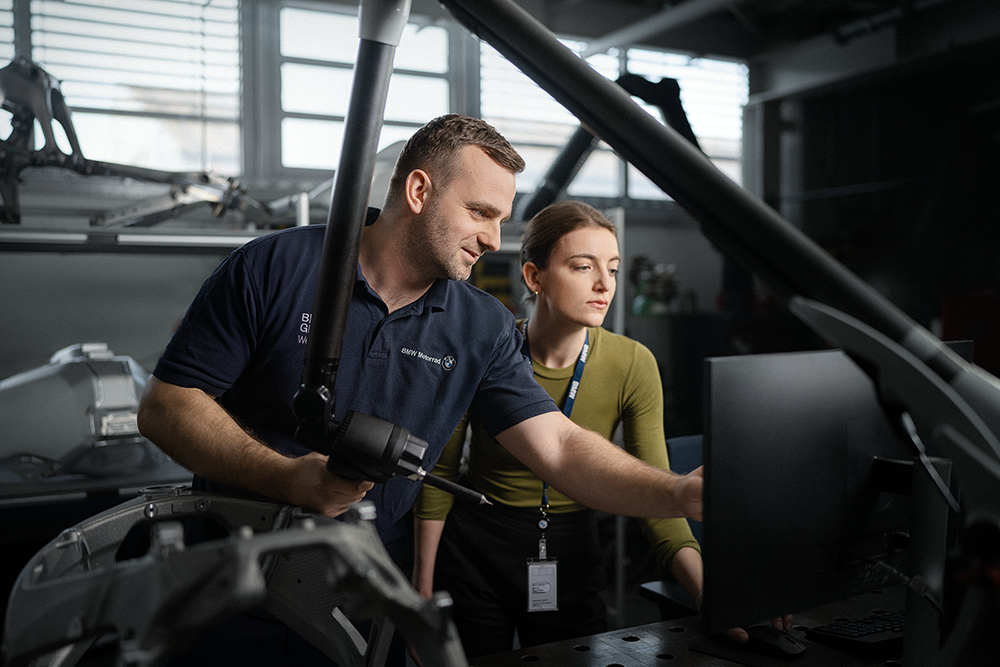 Two colleagues discuss data on a screen.