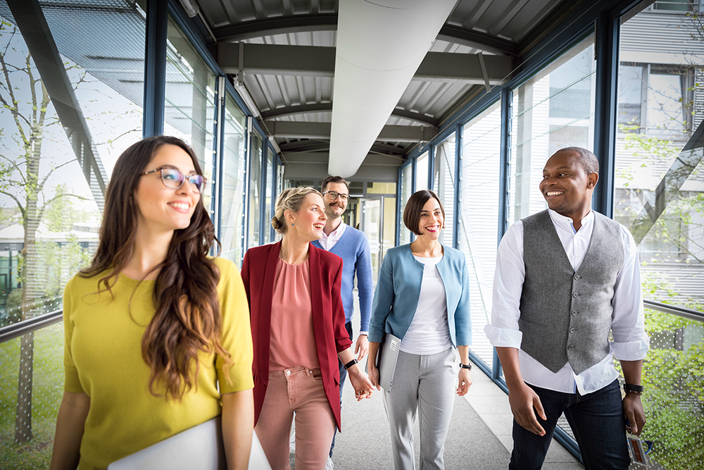 Five members of staff walk along a corridor.