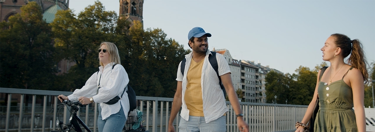 Three colleagues are on a walk next to the Isar in Munich.