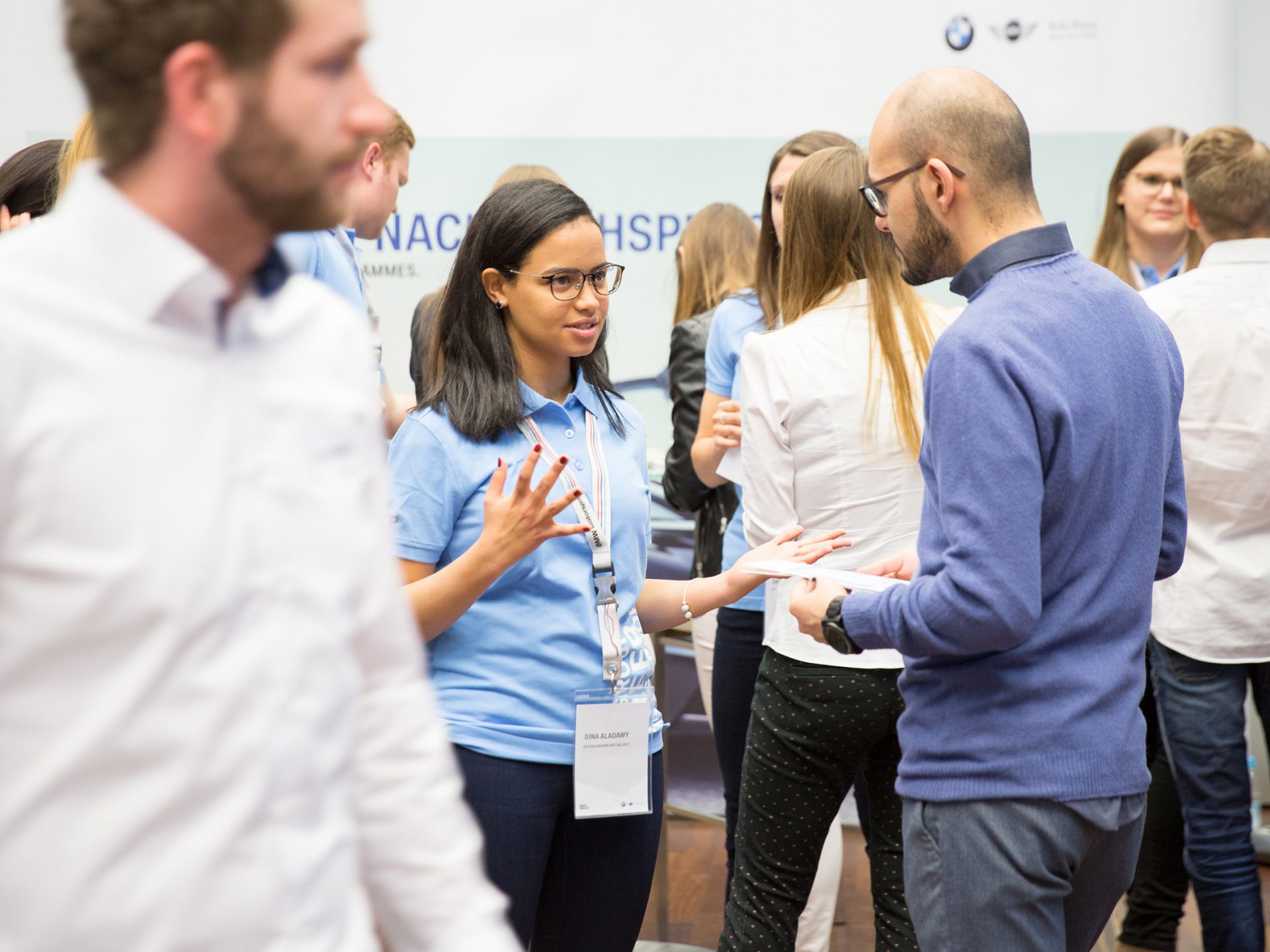 The picture shows a BMW employee explaining about a career at BMW to an interested party.