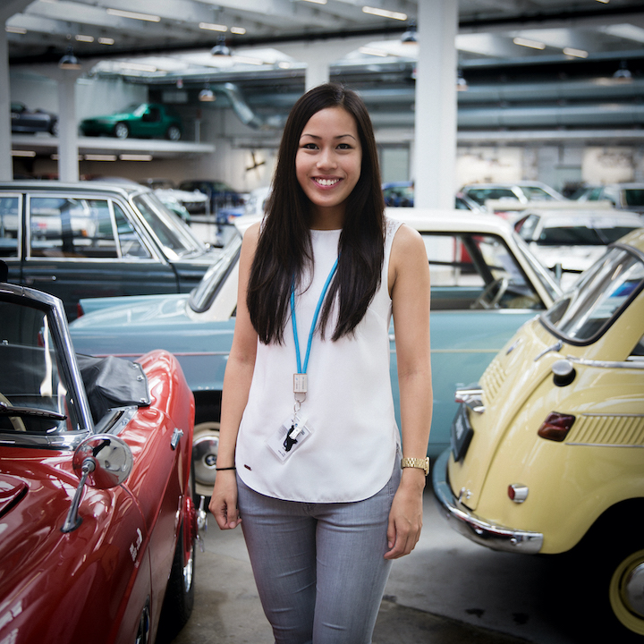 A zoung woman standing between historical BMW vehicles.