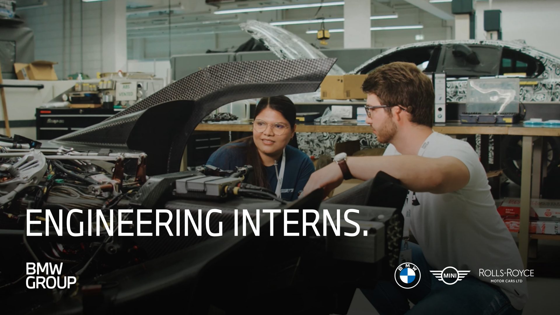 Two people working on a car engine at BMW Group. 