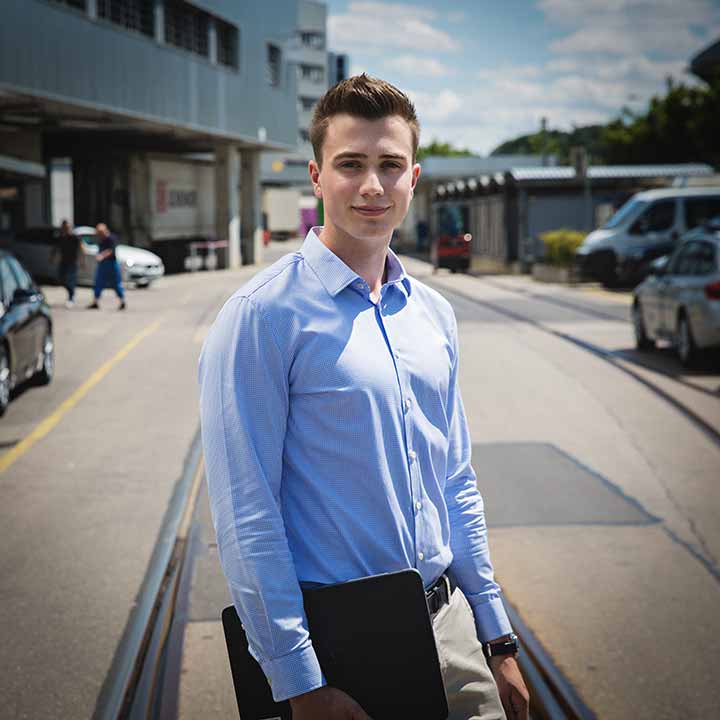 A Intern in logistics with a smile standing on the middle of the street.