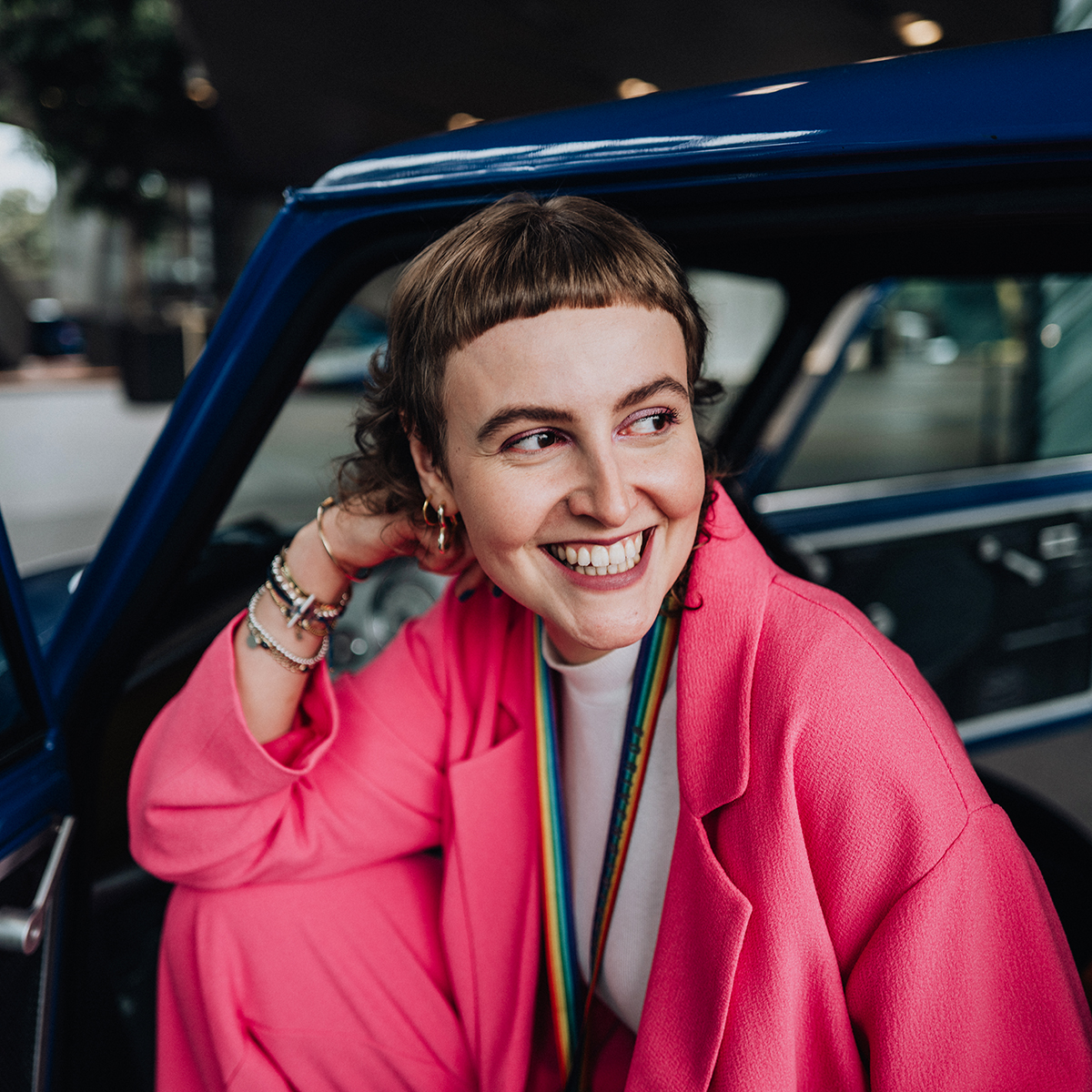 Praktikantin Harriet im Oldtimer-MINI lächelt fröhlich