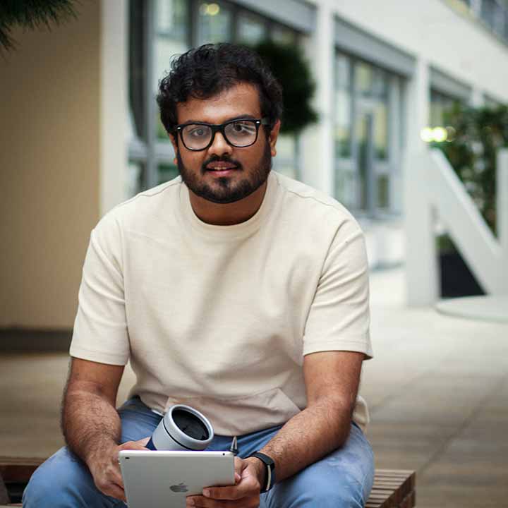 A intern in autonomous driving sitting on a bench and holding a tablet and a cup in his hands. 