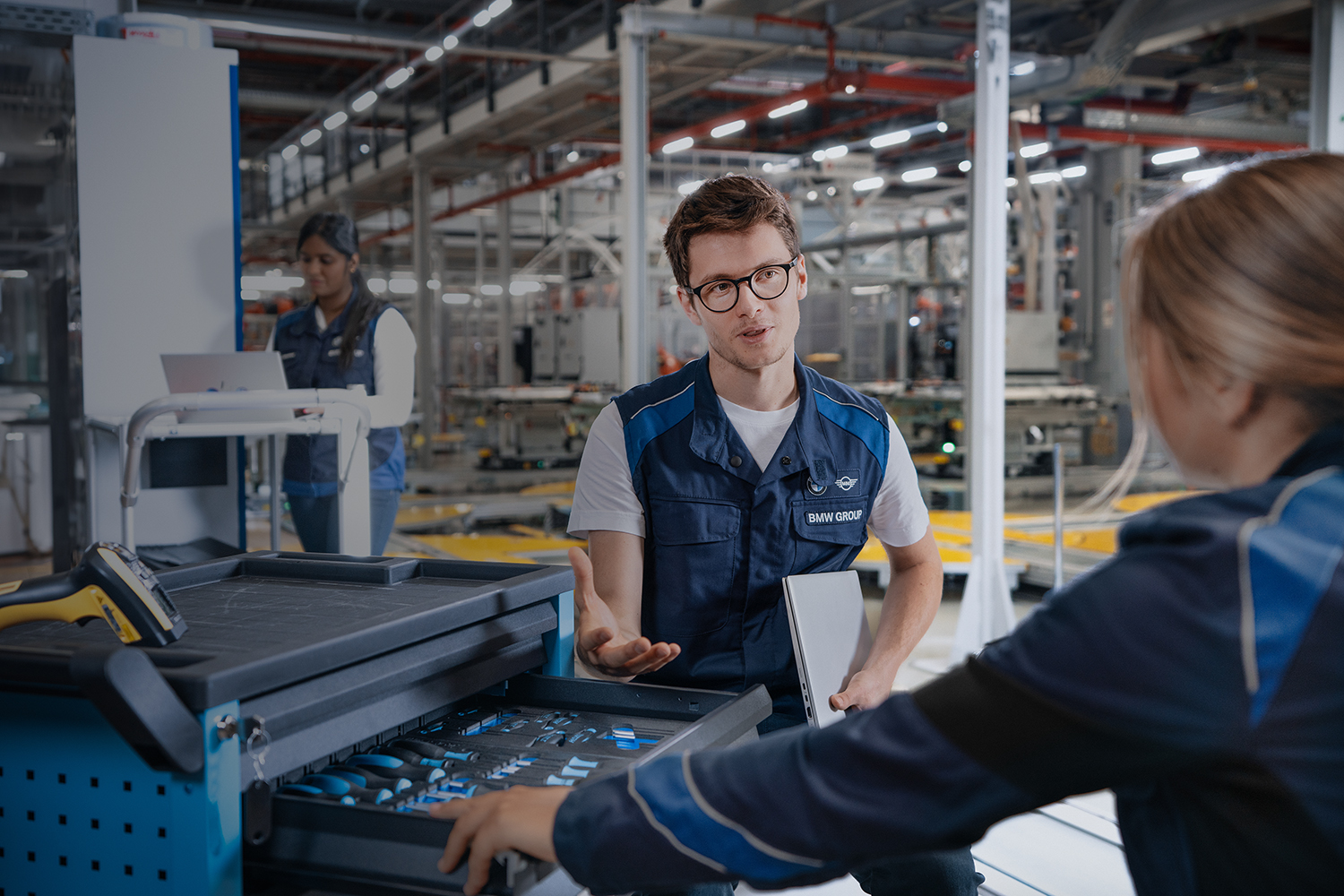 Two students are having a conversation in a BMW Group production environment.