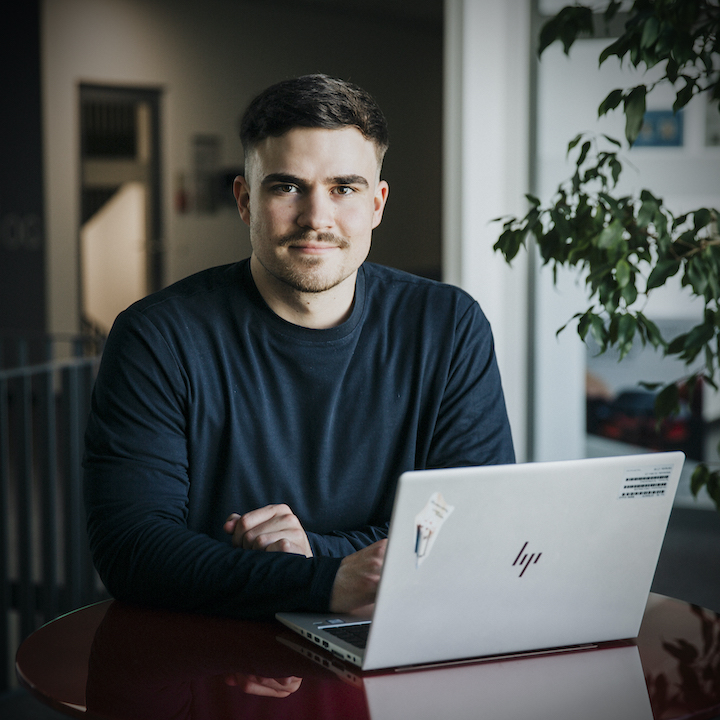 A young working student sitting at a table with a laptop.