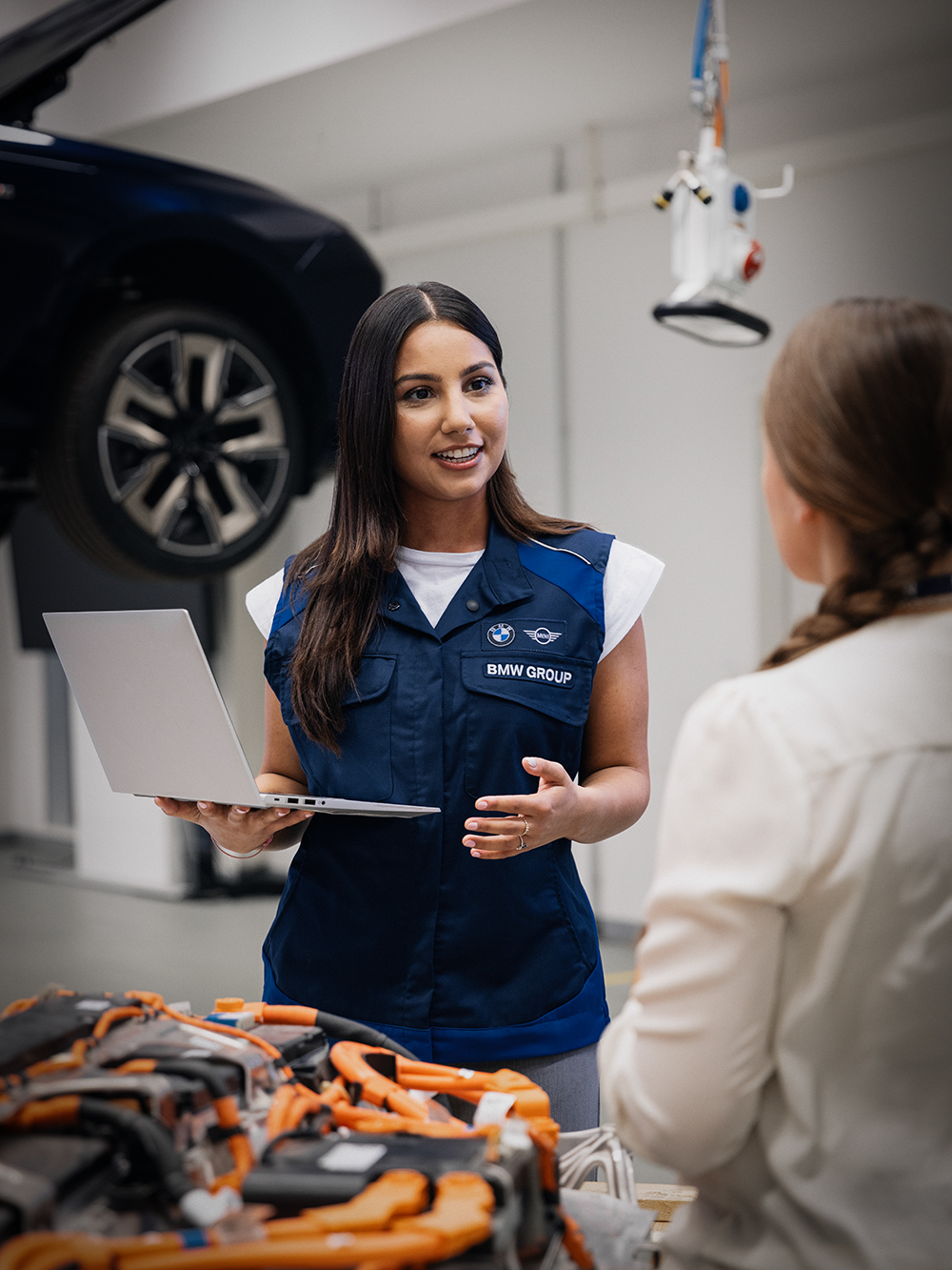 An employee explains the work involved in building a vehicle body to a student trainee.
