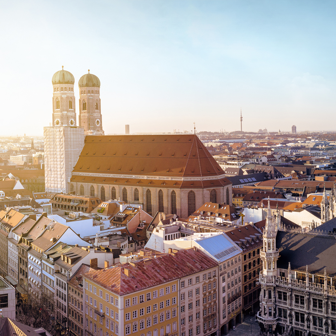 The image shows the Frauenkirche in Munich and the surrounding city.