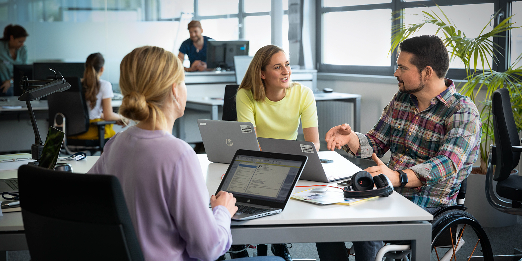 Three colleagues, one of them in a wheelchair, having a meeting