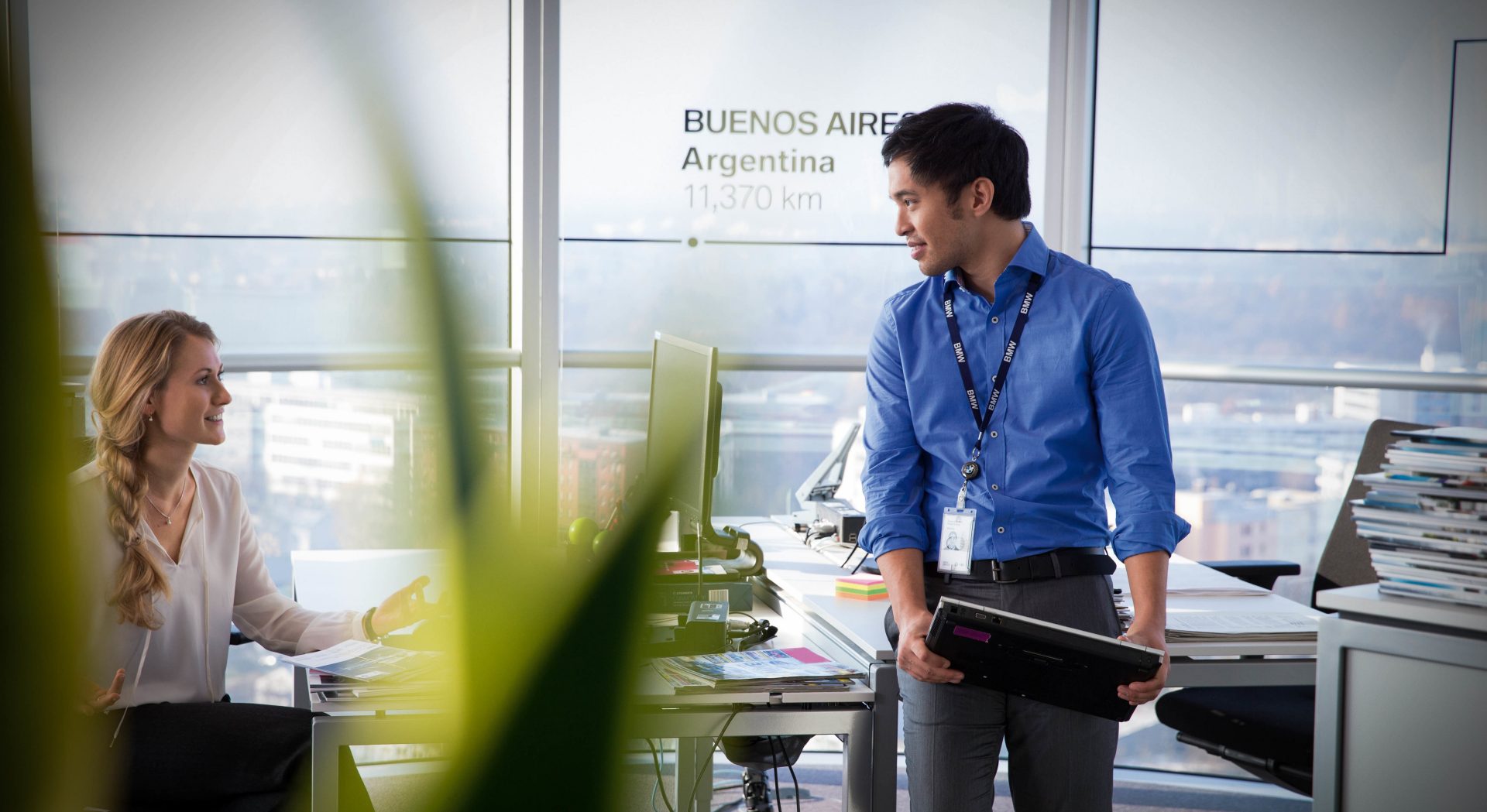 The picture shows two BMW employees talking in a BMW building.