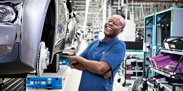 The picture shows a laughing worker in the BMW production.