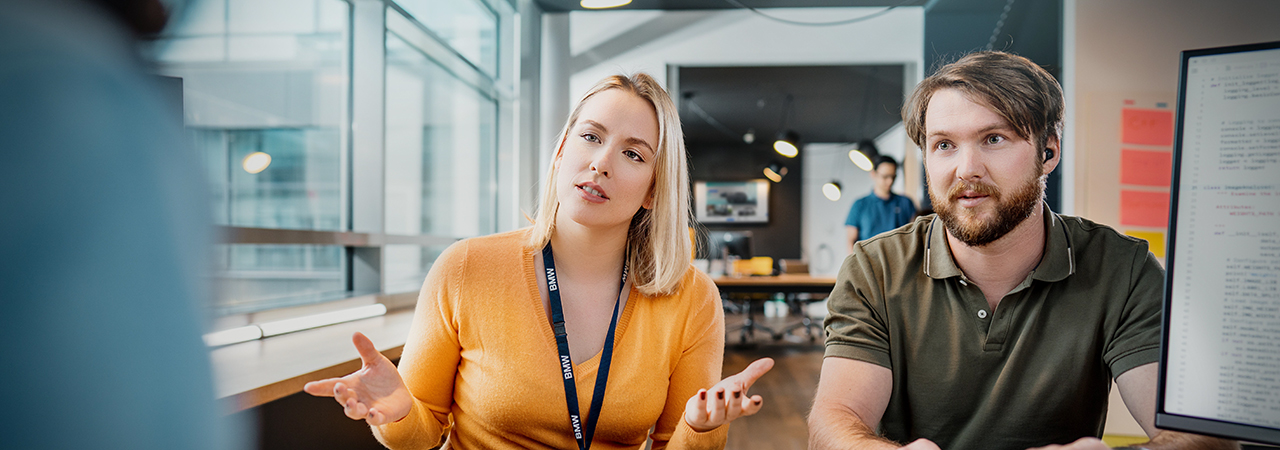 The image shows two colleagues in a canteen.