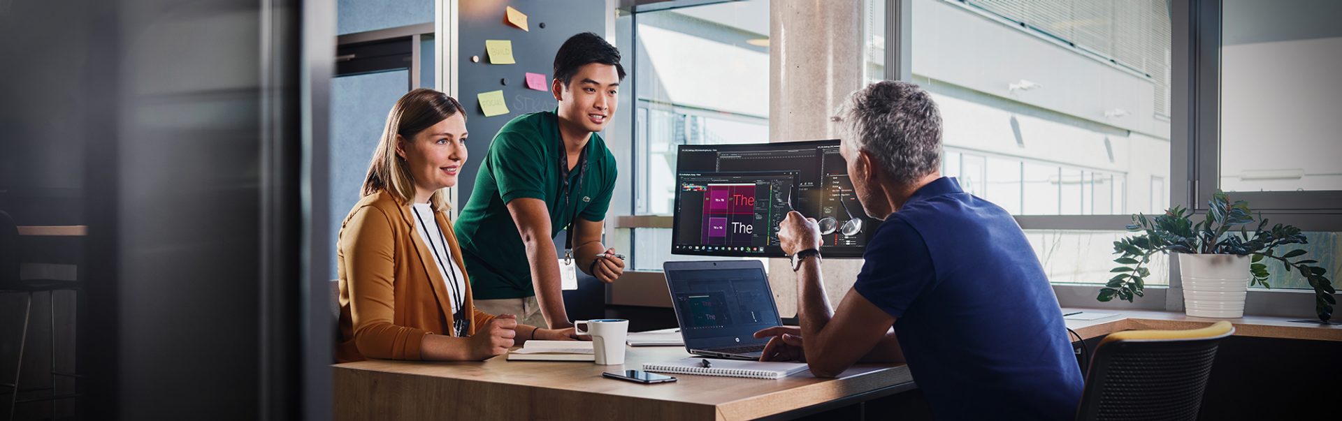 Three IT colleagues chat across the desk