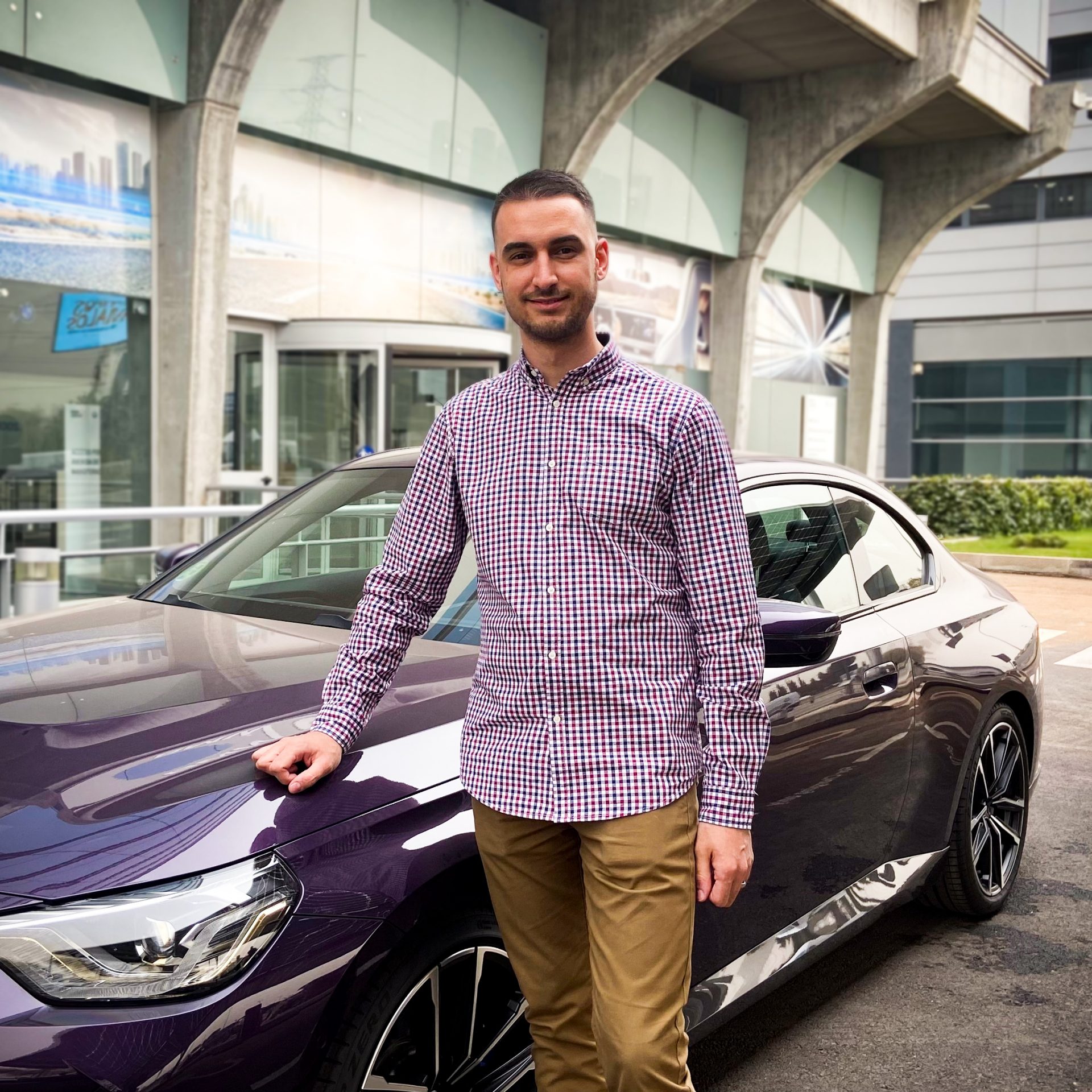 BMW Group employee Kevin in front of a purple 2 series BMW