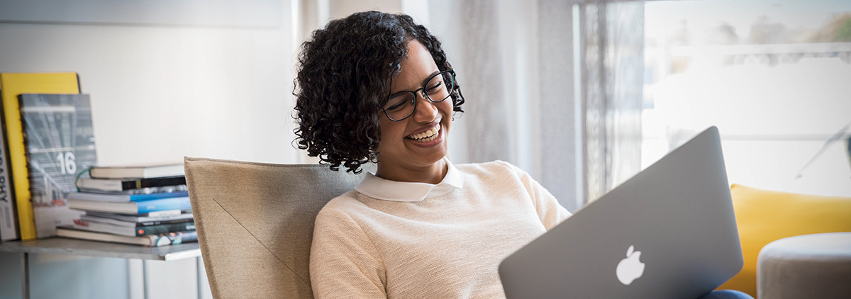 A female colleague is laughing while working with her laptop.