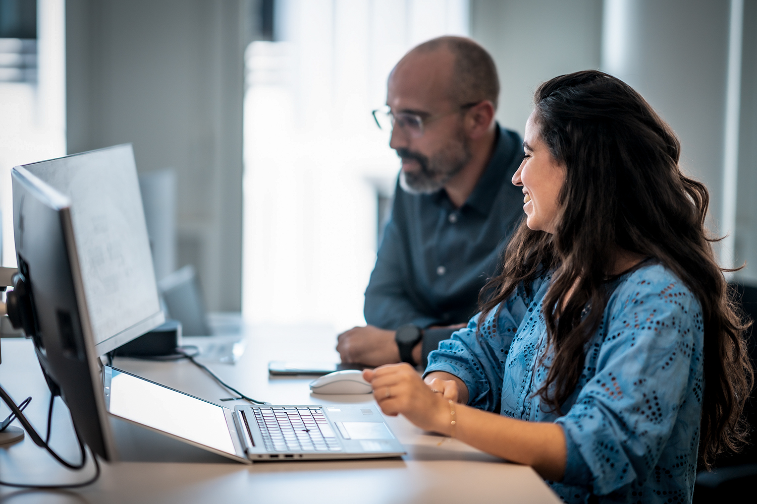 Two colleagues are analysing data on a laptop.