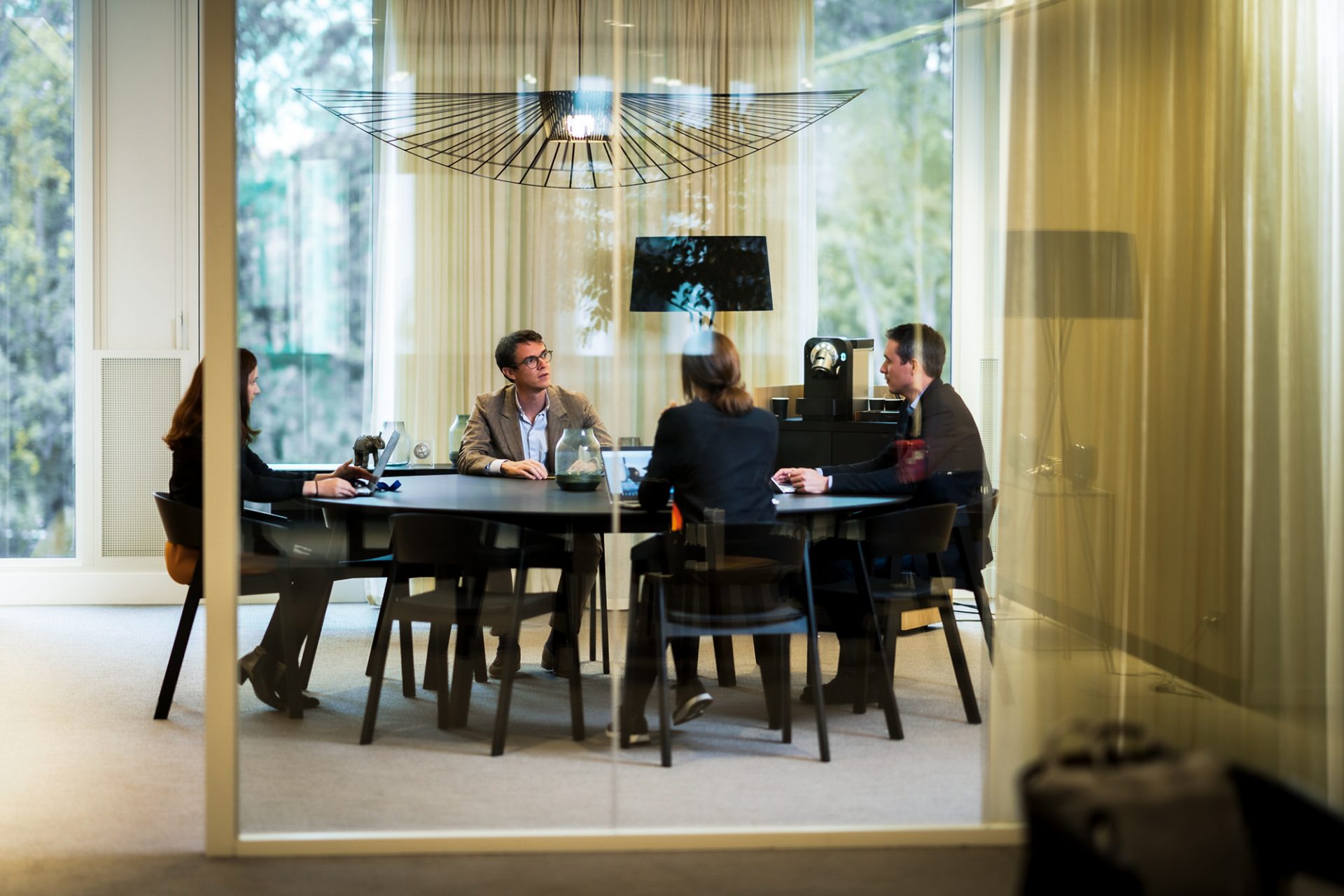 A group of four employees in a meeting room behind a glass wall