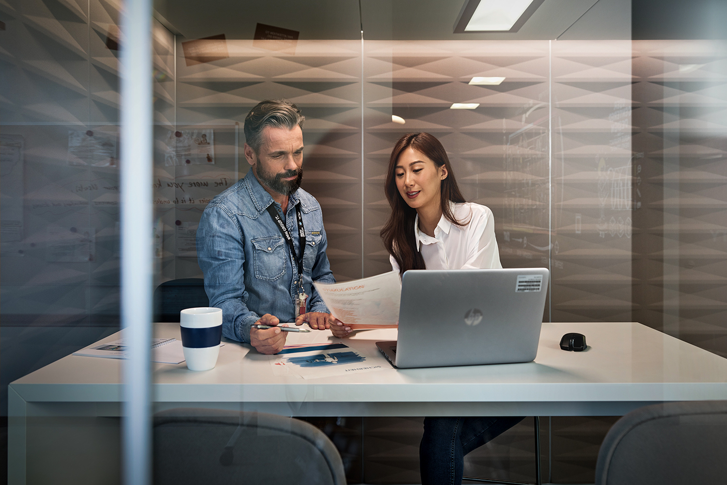 Two colleagues are looking at a booklet in a meeting room