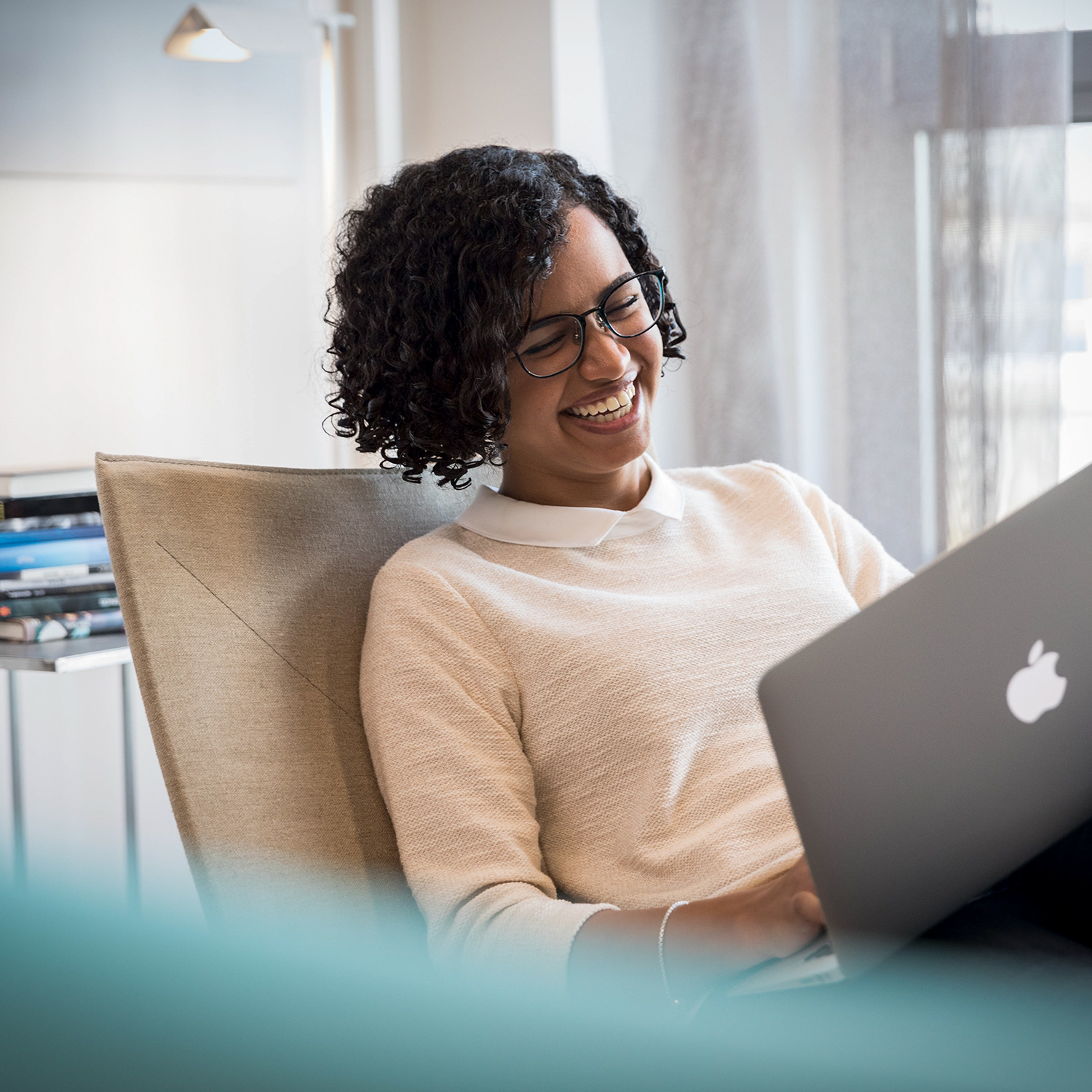 A colleague working with her laptop from home, laughing.