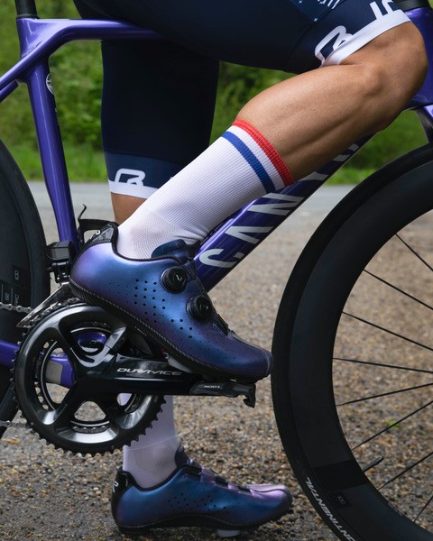 Gros plan sur une jambe posée sur les pédales d'un vélo de course