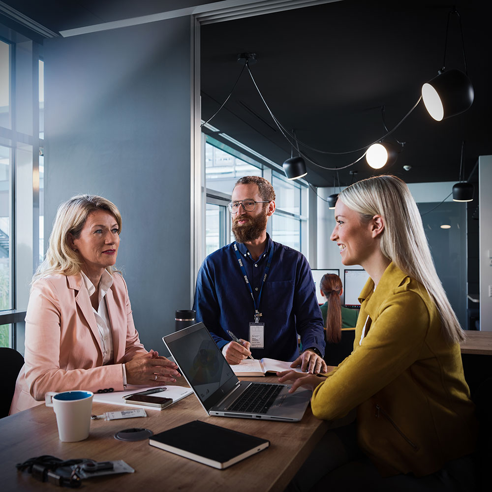 The picture shows three colleagues at a table.