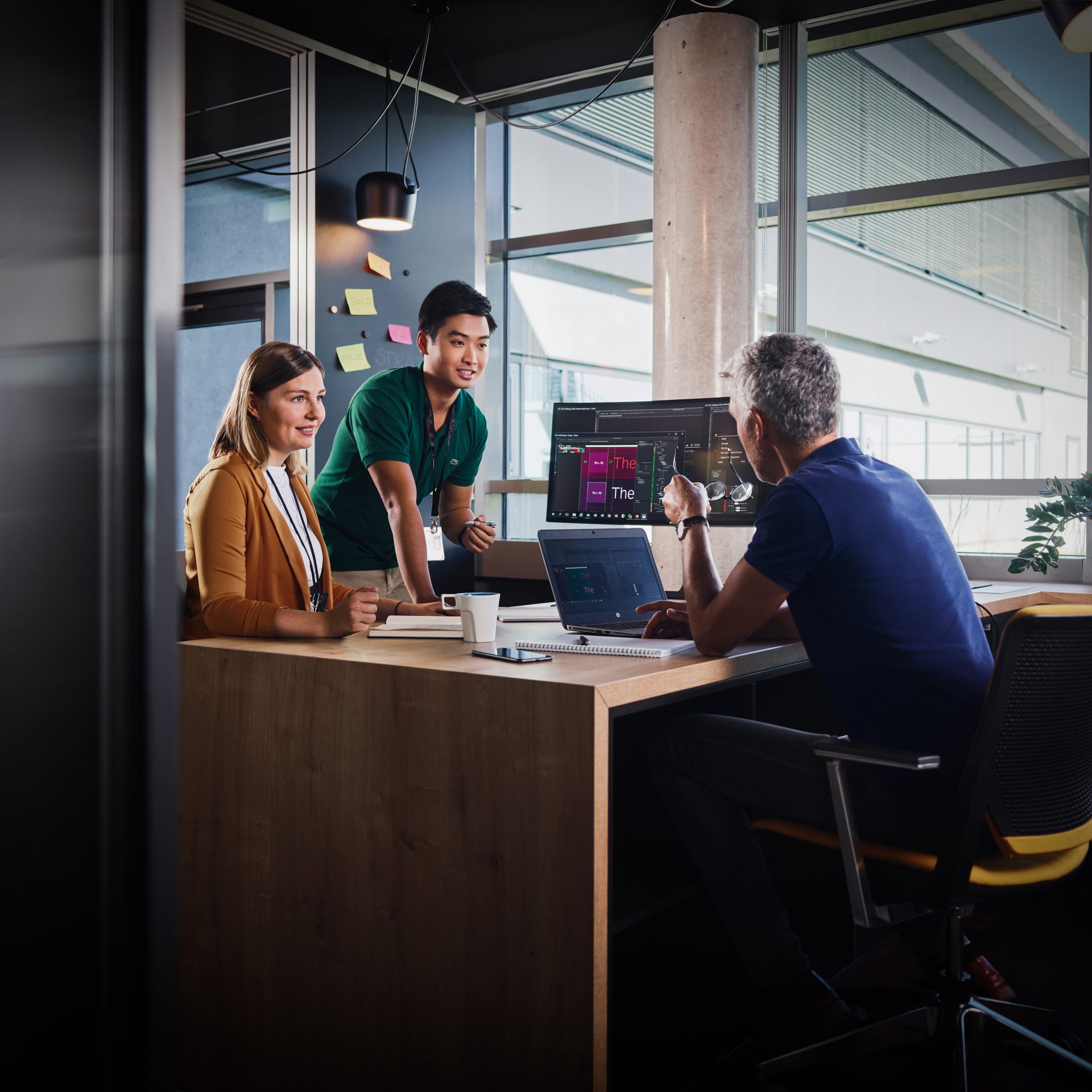 The image shows three employees in a meeting talking.