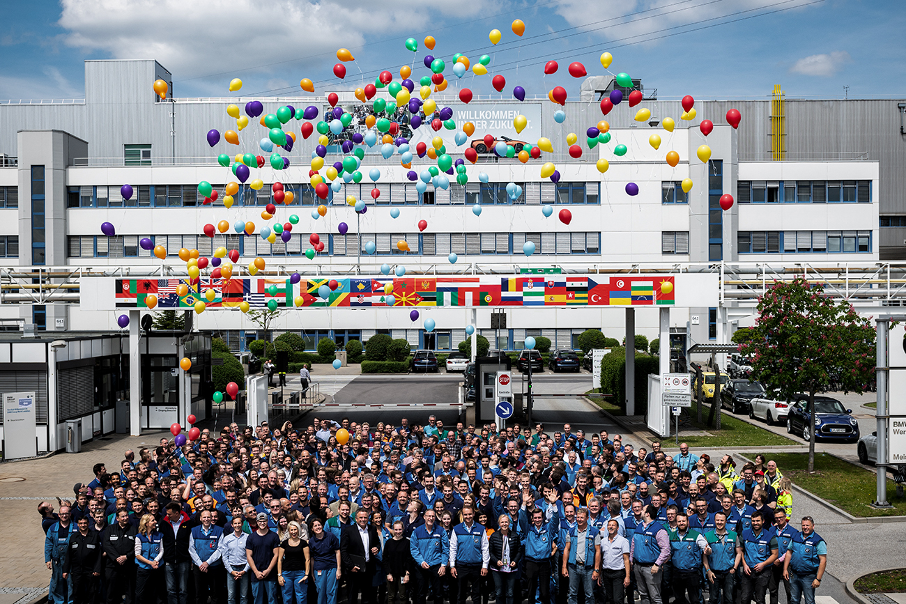 A Group of diverse colleagues at the BMW Group infront of a building letting balloons rise into the sky.