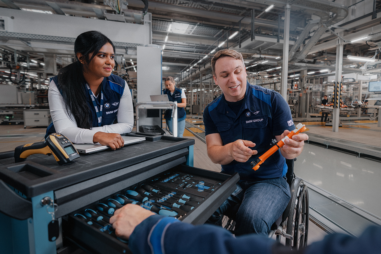 Two colleagues, one in a wheelchair, working in production together.  