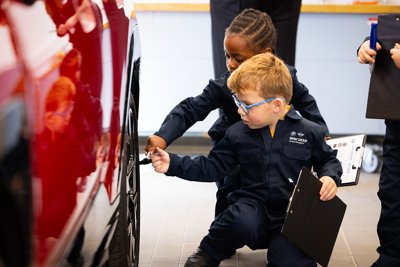 School students inspecting a BMW vehicle during an interactive workshop session.