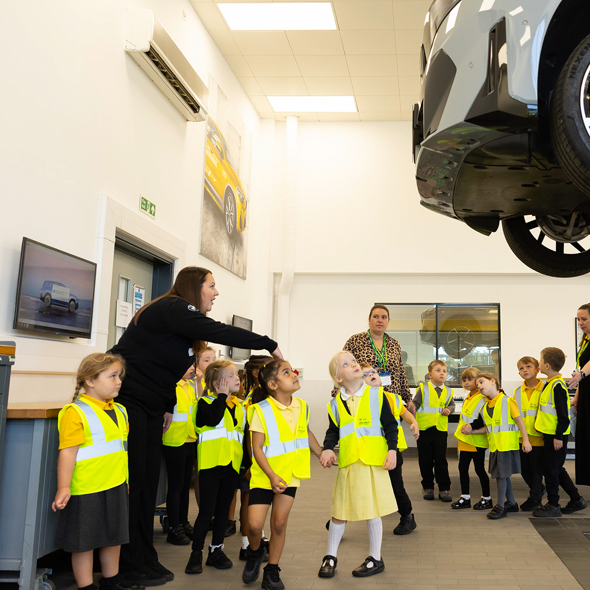 A teacher with a group of pupils exploring a BMW workshop