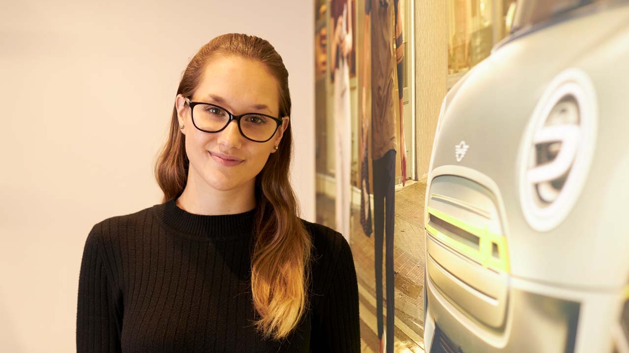 Ruby, a business apprentice standing next to a MINI wallpaper.