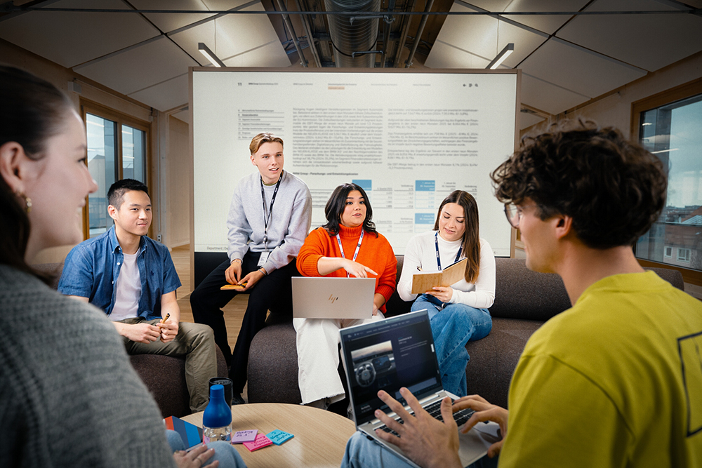 Team meeting in a collaborative workspace discussing ideas and marketing projects using a presentation screen.