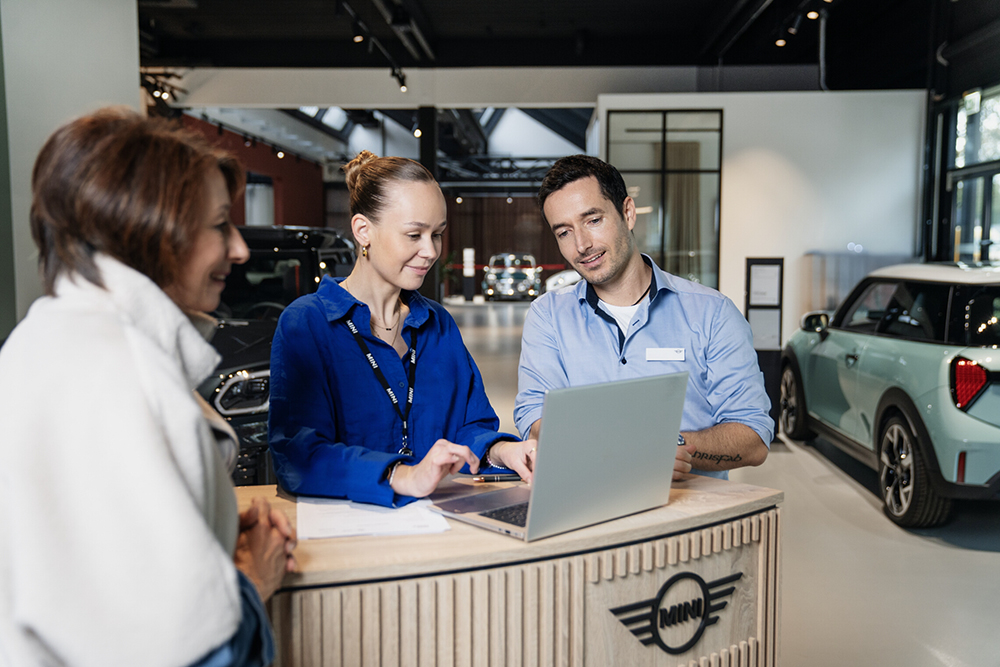 Team members collaborating at a reception desk in an automotive service environment.
