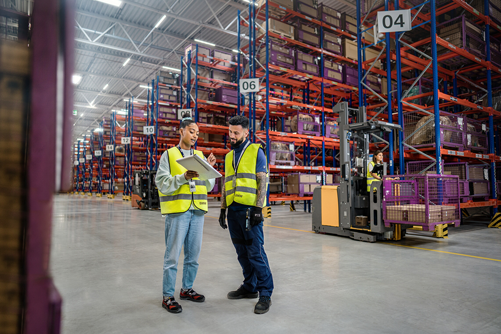 Logistics employees discussing warehouse operations in a distribution centre.