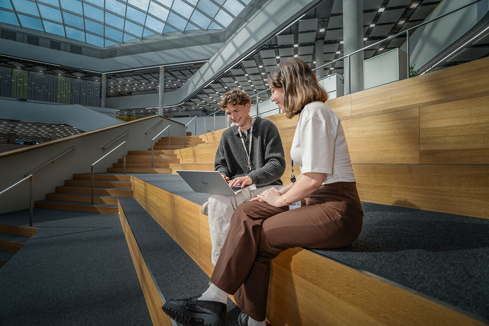Two employees working together and discussing business topics in a modern office atrium.