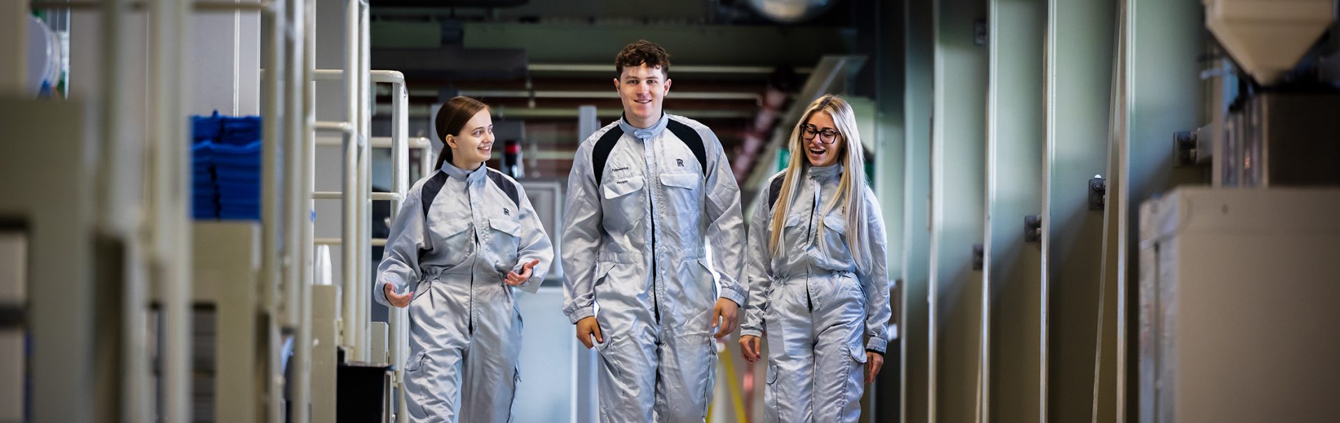 Three young colleagues walking down the production hall