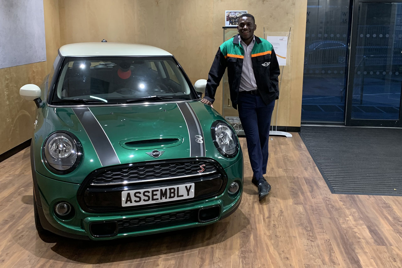 Faith, an assembly planning intern standing next to a green MINI 